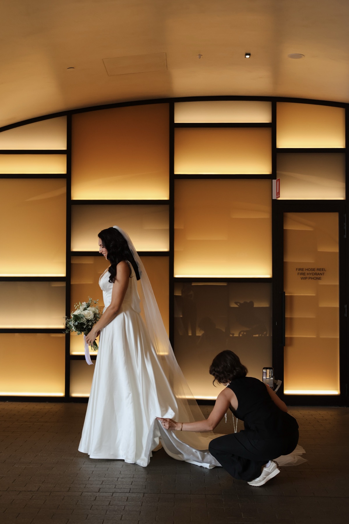 Jaeli adjusting a bride's veil and dress before the ceremony